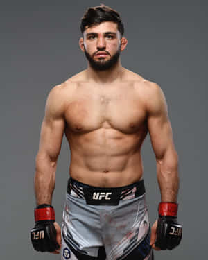 一位赤裸上身的男性MMA拳手，穿著UFC短褲和手套，為工作室肖像擺姿勢。