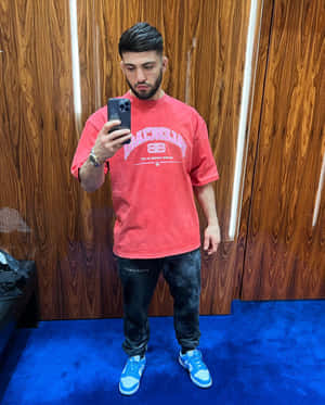 男子身穿紅色T恤和藍色運動鞋在藍色地毯上對著鏡子自拍。