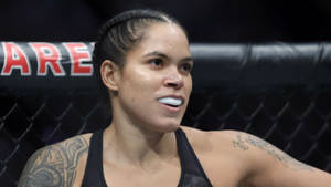 女性MMA拳手，有紋身，戴白色護齒，在八角籠內。