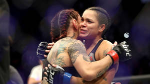 兩位女性MMA拳手在八角籠內賽後擁抱。