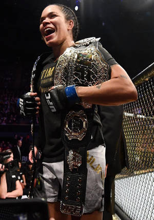 UFC拳手在八角籠內手持冠軍腰帶慶祝勝利。