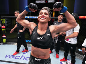 女性MMA拳手在UFC八角籠中高舉雙臂慶祝勝利。 — 運動 壁紙