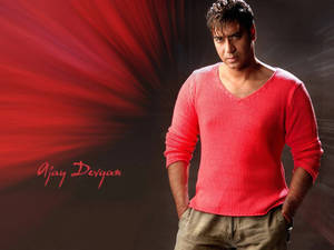 演員 Ajay Devgan 穿著紅色毛衣，背景為紅色放射狀，他的名字被書寫。 — 插畫 壁紙