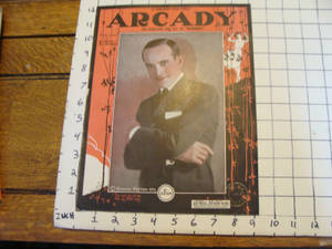 1925年復古Arcady雜誌封面，西裝男子坐在木桌上，桌上放有尺子。 — 荷里活 GIF 壁紙
