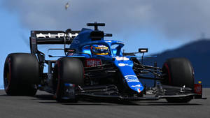 藍黑配色的Alpine F1賽車在賽道上疾馳，輪胎冒出煙霧。