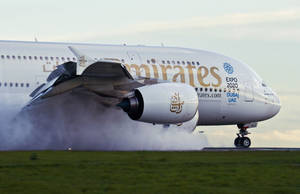 阿聯酋航空A380在黃昏時分於跑道降落，輪胎冒煙