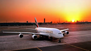 夕陽下跑道上的阿聯酋A380飛機，背景為城市天際線 — 飛機 壁紙