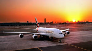 夕陽下的阿聯酋航空飛機在停機坪上，背景為杜拜天際線