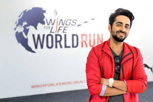 在Wings for Life World Run活動中，身穿紅色外套的男子對著鏡頭微笑。