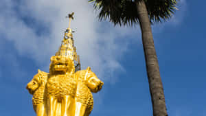 金色三頭獅子雕像在藍天下棕櫚樹旁