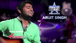 歌手Arijit Singh在舞台上表演，手持結他，紫色燈光。