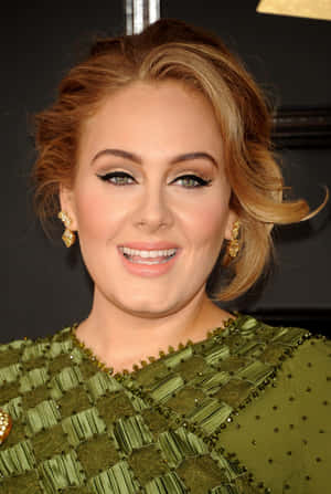 Adele 在活動中穿著綠色珠飾連衣裙和金色耳環。