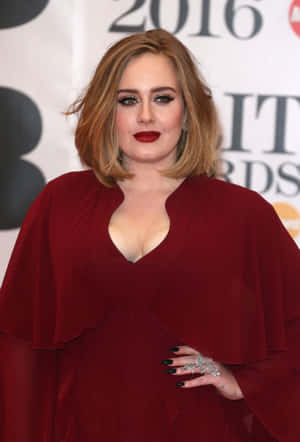 Adele 在2016年全英音樂獎上穿著紅色連衣裙，搭配大膽的紅唇和黑色指甲。