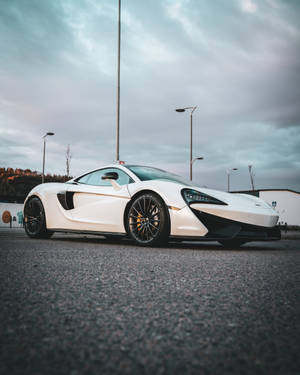 白色McLaren跑車停泊在瀝青路上，背景陰天。