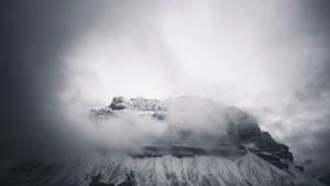 白雪覆蓋的山峰在暴風雨的天空中穿過厚厚雲層聳立。