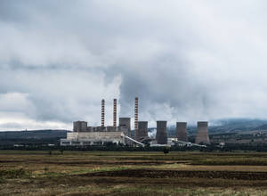 工業發電廠煙囪在陰天下的開闊田野上方排放煙霧。