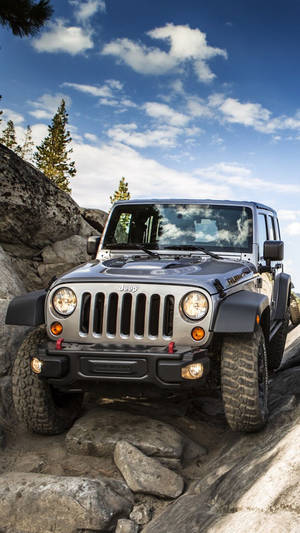 銀色Jeep Wrangler在藍天下攀爬岩石小徑