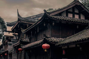 多雲天空下，掛著紅色燈籠的古老中式木建築。 — 唐人街 GIF 壁紙