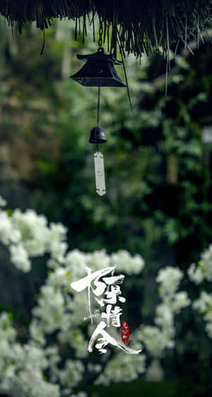 黑色風鈴懸掛在綠色花園中的白色花朵上方，帶有風格化文字。