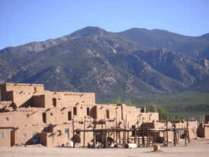 土坯普韋布洛村莊，背景有山脈，天空清澈湛藍