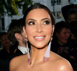 Kim Kardashian 在活動中微笑，佩戴粉紅和銀色耳環。