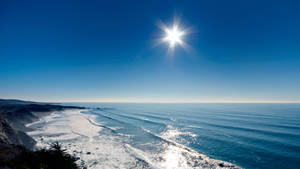 陽光在清澈的藍天下沿著沙灘的海浪上閃爍。