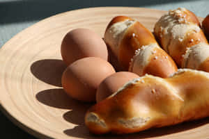 在明亮陽光下，木盤上的棕色雞蛋和鹽味蝴蝶酥卷。 — 早餐動圖 壁紙