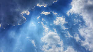 陽光穿過蓬鬆的白雲，在明亮的藍天中閃耀。 — 藍天 壁紙