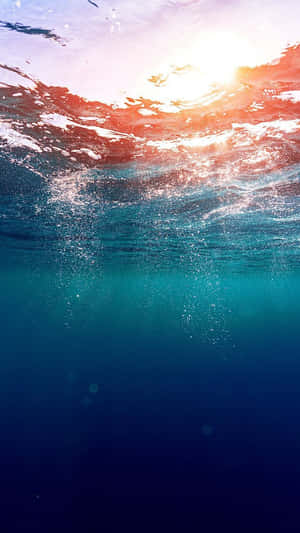 陽光穿過海浪，營造出寧靜的水下場景。 — 手機 壁紙