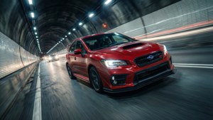 紅色Subaru WRX STI在夜間隧道中疾馳，帶有動態模糊效果。