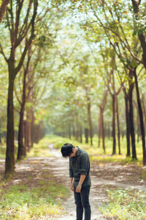 一個年輕男子在陽光明媚的日子裡獨自走在綠樹成蔭的森林小徑上。