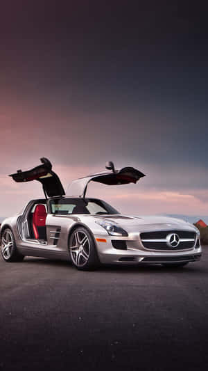 日落時分，銀色平治 SLS AMG 在道路上打開鷗翼車門。