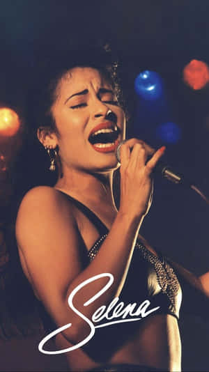 Selena Quintanilla 在舞台上表演，燈光色彩繽紛，她的名字寫在下方。