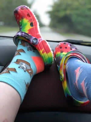 雙腳穿著彩色Crocs和圖案襪子，擱在汽車儀表板上。