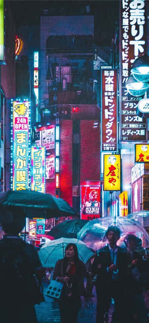 行人撐傘走過雨夜霓虹燈下的東京街道。