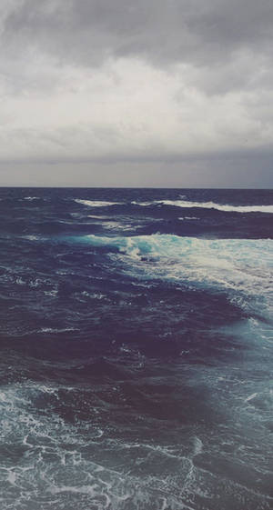 在暴風雨的灰色天空下，波濤洶湧的海浪。