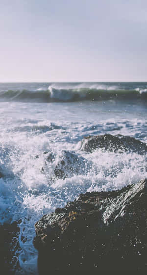海浪拍打深色岩石，泛起白色泡沫