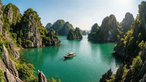 一艘小船在碧綠海灣中漂流，兩側是覆蓋著綠色的高聳石灰岩懸崖。