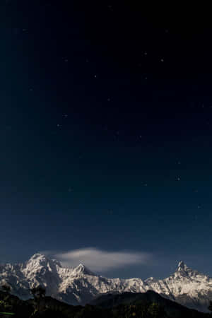 繁星夜空下的雪山山脈，帶有一朵發光的雲。