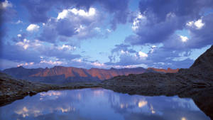 山湖映照黃昏時分的紫色雲彩和金色山峰