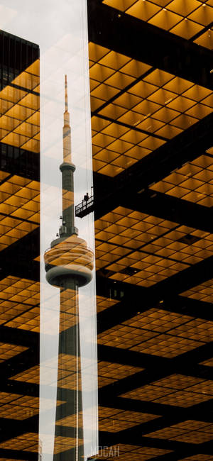 CN塔倒映在帶有金色網格圖案的玻璃建築物上。 — Pixel 10 Pro 壁紙
