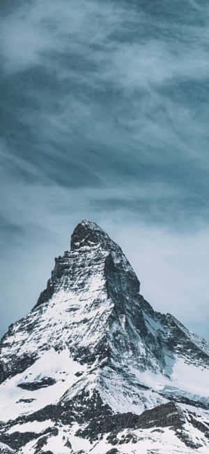 白雪覆蓋的山峰在冷藍色天空下穿過戲劇性的雲層升起。 — Oppo 壁紙