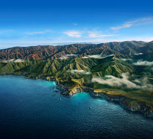 海岸山脈，霧氣瀰漫的山谷和碧綠色的海水，天空清澈湛藍。 — 行星 壁紙