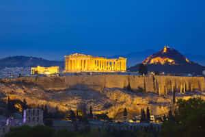 帕德嫩神廟在雅典衛城山丘上於黃昏時亮起燈光 — MacBook Pro M4 壁紙