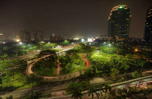 夜景，發光的建築物和穿過綠色空間的移動汽車光跡。 — 午夜 壁紙