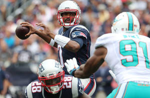 NFL四分衛在現場比賽中投擲橄欖球，防守球員逼近。