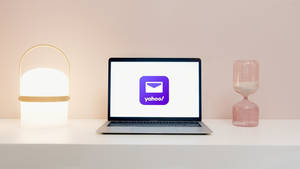 在乾淨的書桌上顯示Yahoo標誌的筆記型電腦，配有燈和沙漏。