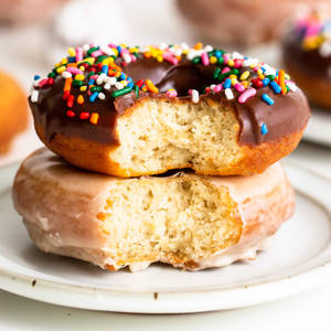 兩個被咬過的冬甩，一個有朱古力和糖針，另一個有糖霜，在白色碟上。