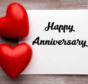 兩個紅色心形旁邊有一張寫著 Happy Anniversary 的卡片。
