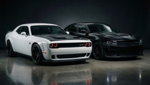 兩輛Dodge Challenger SRT Hellcat肌肉車，白色和黑色，帶紅色制動卡鉗，停在反光地板上。